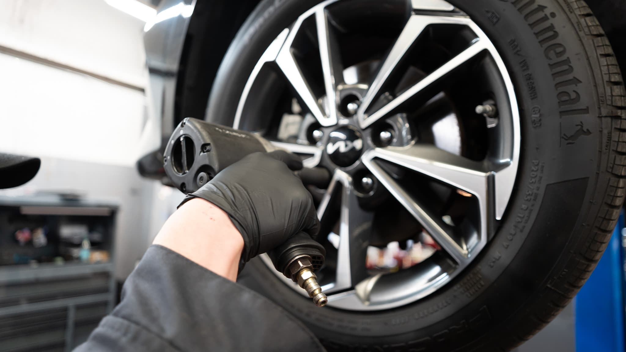 Technician using an impact wrench near a wheel during brake service.